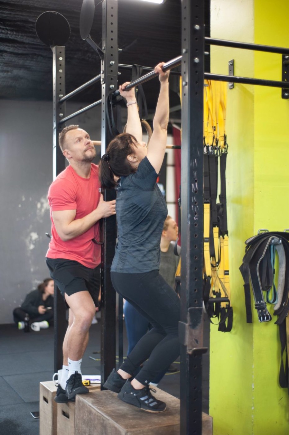 Coach helping an athlete during a pull-up progression